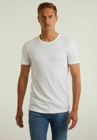 Tricou alb din bumbac, cu mâneci scurte, design cu guler rotund și un mic logo brodat pe piept. Purtați-l cu blugi albaștri.