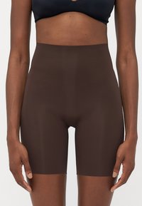 Hoge taille brown shapewear short gemaakt van gladde stof, ontworpen voor een strakke pasvorm, met een lengte tot halverwege het bovenbeen en een naadloze uitstraling.