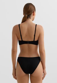 Čierna rebrovaná bikiny sada so nastaviteľnými ramienkami, zapínaním na háčik vzadu a dizajnom nohavičiek s mierne zvýšeným pásom.