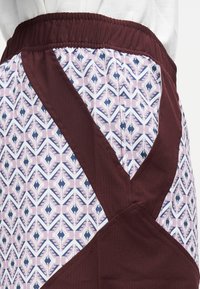 Jupe-short bordeaux avec un surplis à motifs en rose, marine et blanc présentant des dessins géométriques. Taille élastique douce pour plus de confort.