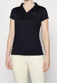 Svart polo skjorta med V-hals och korta ärmar, tillverkad av slätt material. Har en liten broderad logotyp på vänster bröst.