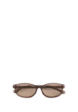 Bruine doorschijnende ovale zonnebril met getinte glazen en smalle pootjes geplaatst tegen een witte achtergrond.