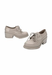 Scarpe in pelle sintetica beige con punta tonda, design con lacci e tacco spesso. Presentano cuciture attorno alla suola.