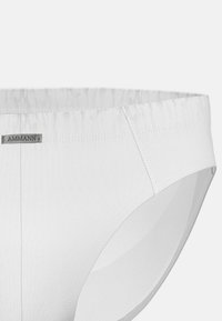 Culottes blanches en coton pour femmes, avec une texture lisse, une taille élastique et une petite étiquette grise avec "AMMANN" cousue à l'avant.