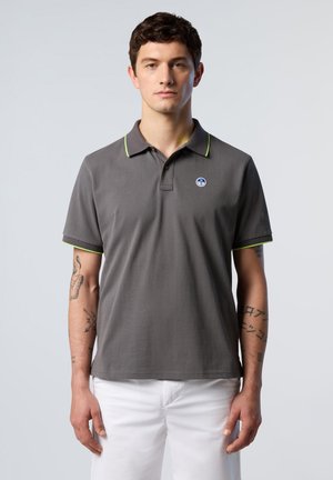 Polo grigio con colletto verde e accenti sulle maniche, caratterizzato da un piccolo logo blu sul lato sinistro del petto. Il tessuto appare liscio e leggero.