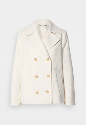 Manteau blanc croisé en tissu texturé, ornée de grandes boutons dorés, de revers crantés et de poches latérales.