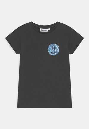 Zwarte katoenen t-shirt met een cirkelvormige blauwe sequined glimlach op de borst. Korte mouwen en een ronden hals ontwerp.