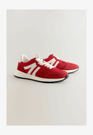 Punased spordijalatsid, mis on valmistatud seemisnahast ja sünteetilisest materjalist, valgete triipude, nööpide ja musta kummitaldaga.