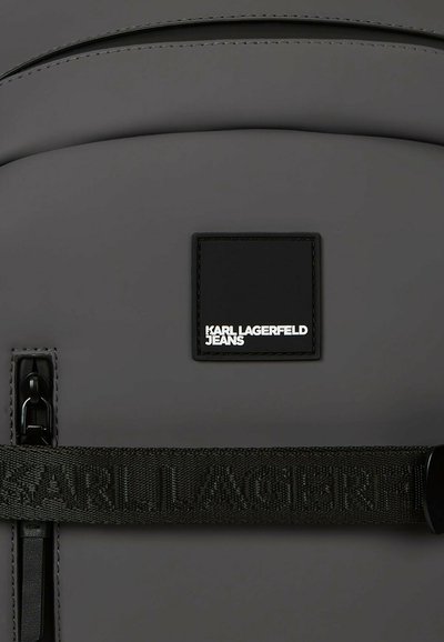 Sac à dos noir Karl Lagerfeld Jeans avec une poche zippée à l'avant et une sangle marquée sur le devant.