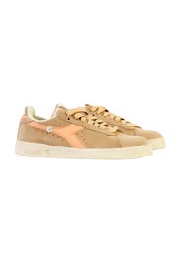 Baskets en suède beige avec des accents roses, à lacets, surface texturée et semelle en caoutchouc blanc avec un léger logo sur le côté.