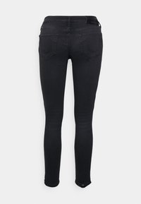 Jeans ajustados negros con una textura suave, que cuentan con dos bolsillos traseros con un diseño en forma de diamante y un logo sutil en la cinturilla.