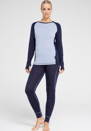 Lys blå langærmet top med marineblå accenter, parret med tætsiddende marineblå leggings med kontrasterende blå syninger. Blødt stof, atletisk pasform.