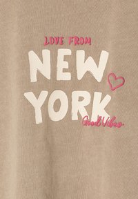 Beige Baumwollhemd mit fettem, weißen Text "NEW YORK" und pinken Akzenten, einschließlich "Love From" darüber und "Good Vibes" darunter.
