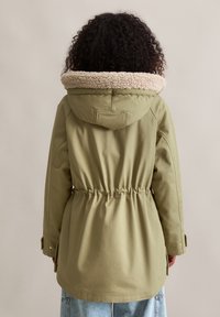 Groene parka jas met een zachte beige fleece-gekraagde capuchon, trekkoord in de taille en lange mouwen, met een gladde stofafwerking.
