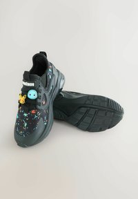 Sorte sneakers med et sprøjtmalingsdesign i flere farver. Har Pokémon-tema mærker og en tekstureret gummisål.