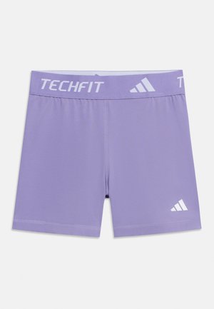 Lawendowe spodenki kompresyjne Adidas Techfit z markowanym paskiem w talii i logo na lewej nodze, zaprojektowane do noszenia podczas aktywności sportowej.