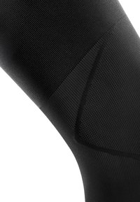 Black compression legwear with a textured, ribbed surface. Features contoured sections for fit and support, emphasizing functionality and comfort.