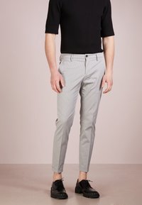 Light gray patterned trousers with a slim fit, side pockets, and a button closure. Paired with a fitted black ribbed short-sleeve top and black shoes.
