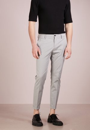Light gray patterned trousers with a slim fit, side pockets, and a button closure. Paired with a fitted black ribbed short-sleeve top and black shoes.