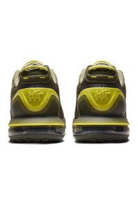 Gröna och gula sneakers med en överdel i mesh och syntetmaterial, vadderad krage och synlig luftkuddar i sulan. Har texturerade detaljer.