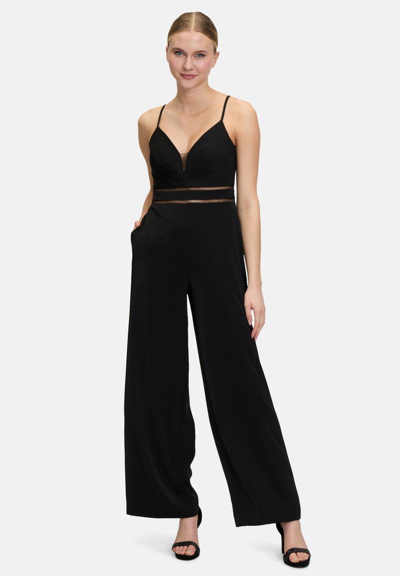 Zwarte jumpsuit met een diepe V-hals en dunne bandjes, voorzien van een doorschijnend taillepaneel en brede broekspijpen. Zacht materiaal met zakken.