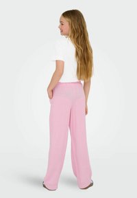Pink, wide-leg trousers with a soft, lightweight fabric and elastic waistband. Paired with a white short-sleeve shirt.