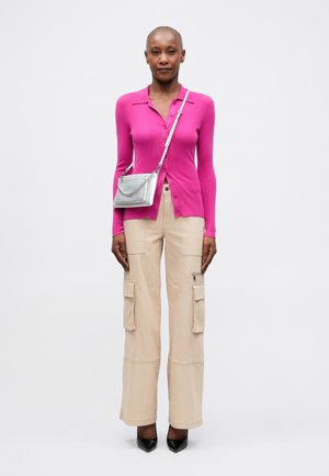 Tight rosa ribbad cardigan med knappstängning, kombinerad med beiga vida cargobyxor med sidofickor, och eleganta svarta spetsiga klackskor.