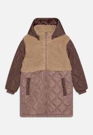 Veste rembourrée avec un haut en fausse fourrure beige, une partie inférieure en tissu matelassé marron, une capuche et des poignets élastiques. Elle dispose de deux poches latérales.