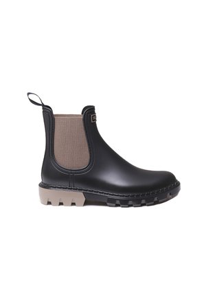 Black rubber Chelsea boot with beige elastic side panels, textured surface, and rugged gray outsole with deep treads.
