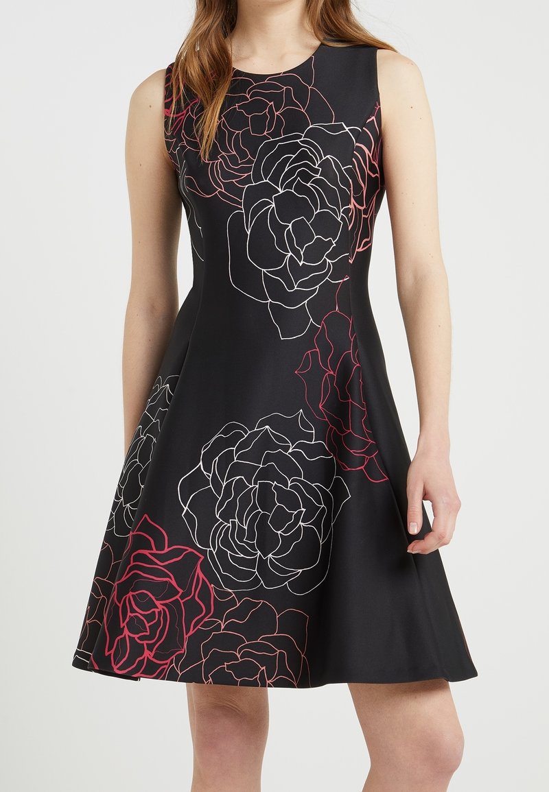 Svart A-linjeformad klänning med stora vita och röda blommönster, utan ärmar, slät textur och en utsvängd silhuett.
