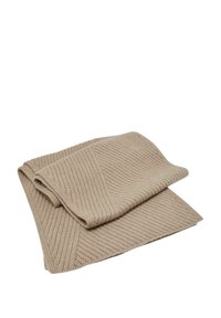 Manta de color beige con textura acanalada, doblada con un borde suave. Presenta un patrón uniforme y una apariencia suave y acogedora.