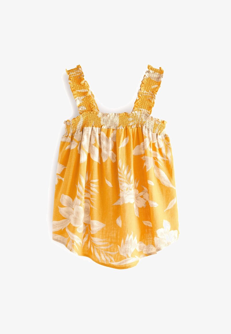 Barboteuse bébé jaune avec imprimé floral blanc, corsage froncé et bretelles à volants sur fond blanc.