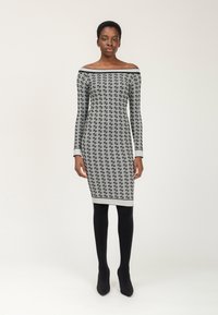 Schwarz-weiß gemustertes schulterfreies Kleid mit langen Ärmeln, figurbetontem Schnitt und einfarbigem weißen Besatz an Hals- und Saum.