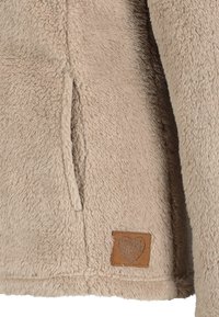 Veste polaire beige avec une poche latérale et un patch en cuir marron en bas orné d'un motif en forme de cœur "LOVE ME".