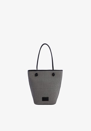 Bolso tipo cesta a rayas blancas y negras con asas largas negras y un pequeño parche rectangular negro cerca del centro inferior.