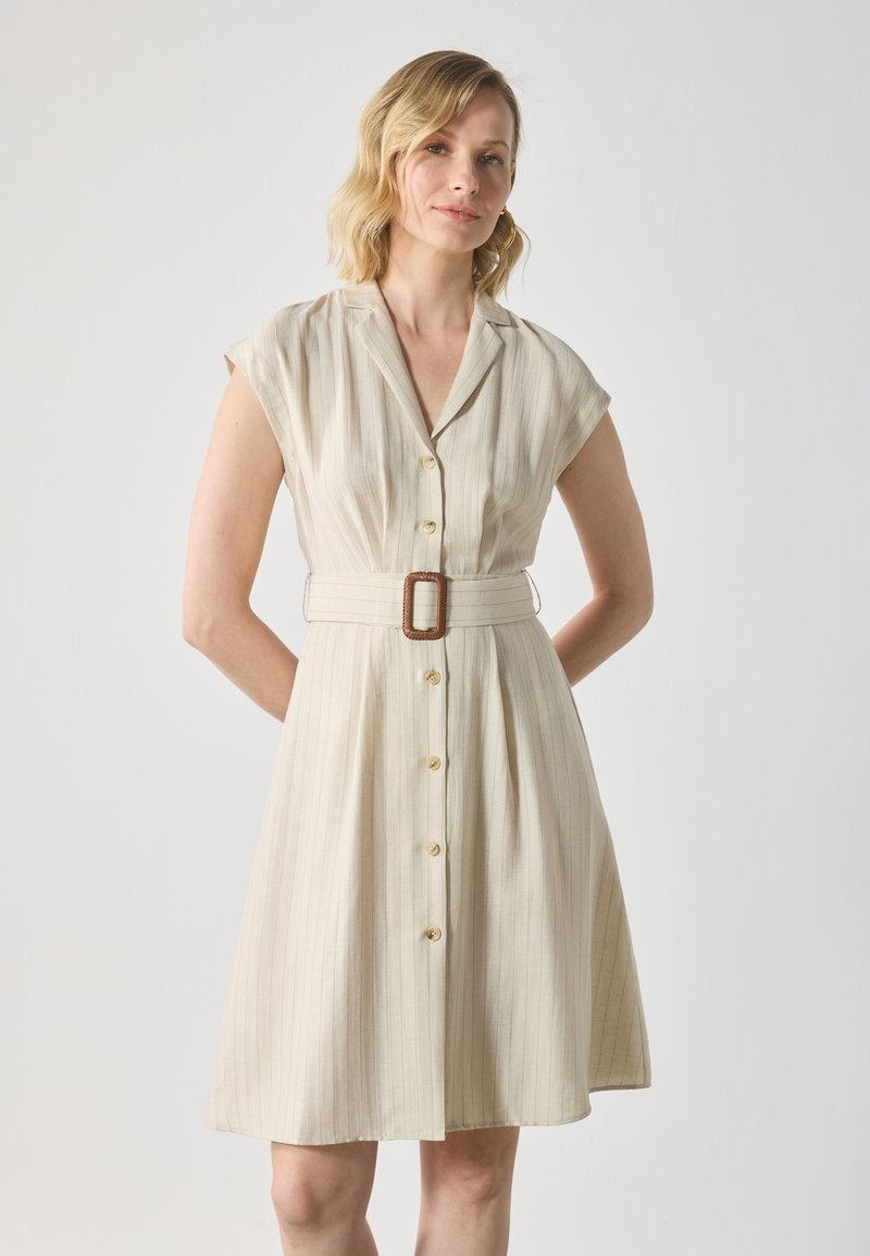 Beige stripete kjole med korte cap-ermer, knappestolpe foran og et tekstilbelte med en rektangulær brun spenne. Glatt tekstur.