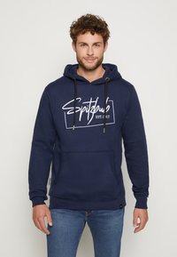 Marineblauwe hoodie met een voorzak, verstelbare trekkoorden en witte grafische tekst "Spitzbub EST. 2017" op de borst. Zachte stoftextuur.
