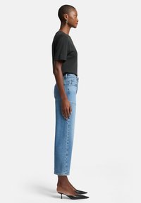 Svart t-shirt med kort ärm i kombination med ljusblå raka jeans och svarta stiletto-klackar. Outfiten har en strömlinjeformad, avslappnad stil.