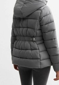 Chaqueta acolchada gris con capucha, con acolchado horizontal, cintura ajustada con cierres a presión y una textura suave y brillante.
