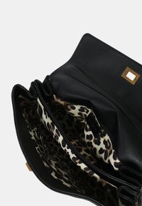 Borsa in pelle nera con fodera a stampa leopardata. Presenta un pattino superiore e diversi scomparti, incluso un comparto con zip per gli oggetti.