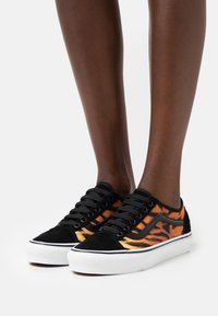 Baskets en daim noir avec motif de rayures de tigre orange, semelles en caoutchouc blanc et lacets noirs. Comprend une bande latérale noire contrastante.