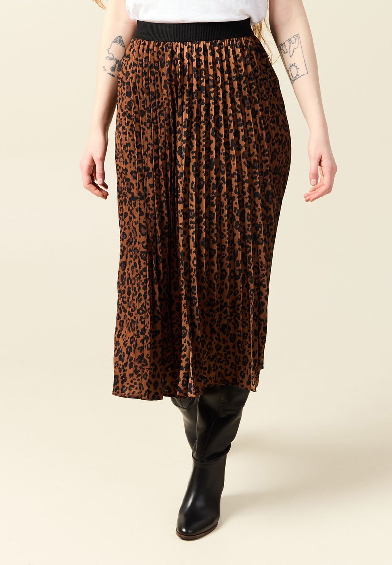 Gonna midi a fantasia leopardata marrone con design plissettato e vita elasticizzata nera, abbinata a stivali in pelle nera al ginocchio.