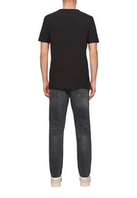 Czarny bawełniany t-shirt z krótkim rękawem, w parze z wyblakłymi czarnymi dżinsami, o standardowym kroju i minimalnych detalach. Miękka tekstura i prosty design.
