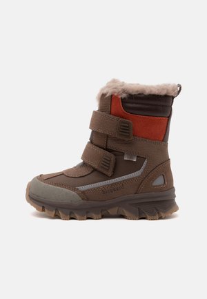 Botte d’hiver marron pour enfant avec double bandes velcro, panneaux orange et brun foncé, doublure en fourrure, semelle robuste et détails réfléchissants.