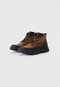 Brune ruskind ankelstøvler med sorte gummisåler, der har sorte snørebånd, shearling kant og Tom Tailor branding på siden.