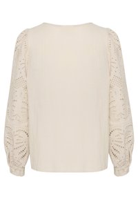 Cream-colored blouse with embroidered lace sleeves, featuring intricate floral patterns and a relaxed fit. Smooth fabric, round neckline.