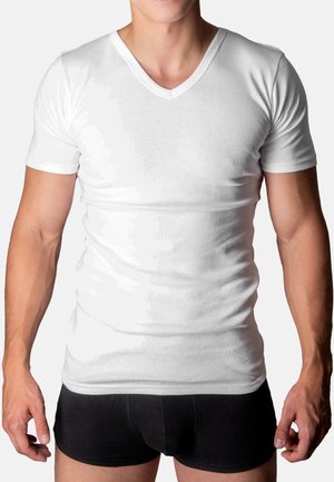 Weißes Baumwoll-V-Ausschnitt-T-Shirt, kurze Ärmel, taillierte Passform, glatte Textur. Getragen mit schwarzen Shorts, die eine körpernahe Silhouette zeigen.