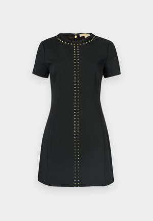 Crna haljina kratkih rukava s okruglim izrezom. Na prednjem dijelu nalazi se okomiti niz zlatnih zakovica, a na leđima skriveni patentni zatvarač.