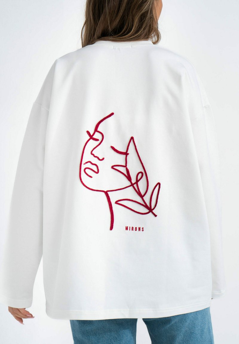 Witte oversized sweatshirt met een rood geborduurd gezicht en bladontwerp op de achterkant. Glad materiaal met een relaxte pasvorm en lange mouwen.