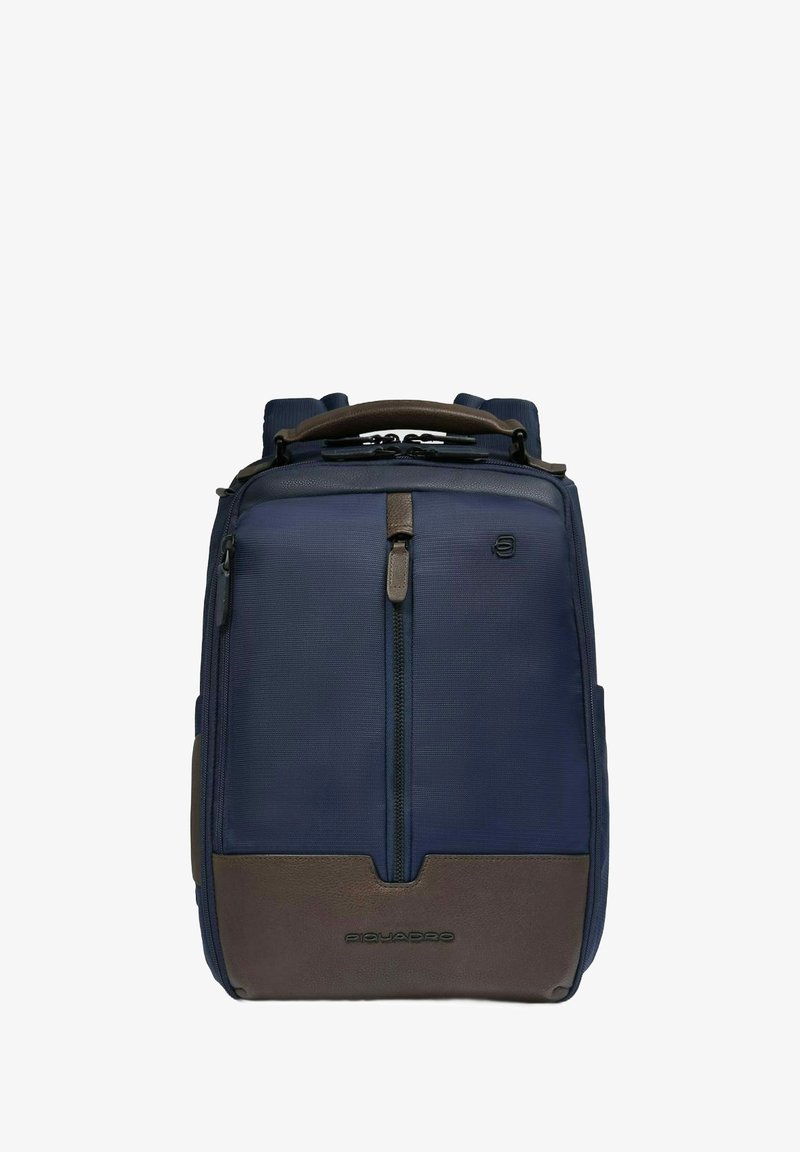 Zaino blu navy con tessuto strutturato, dettagli in pelle marrone, manico imbottito e scomparto frontale con cerniera. Logo del marchio visibile.